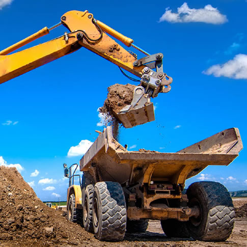 construction vehicle scooping out dirt from dump truck